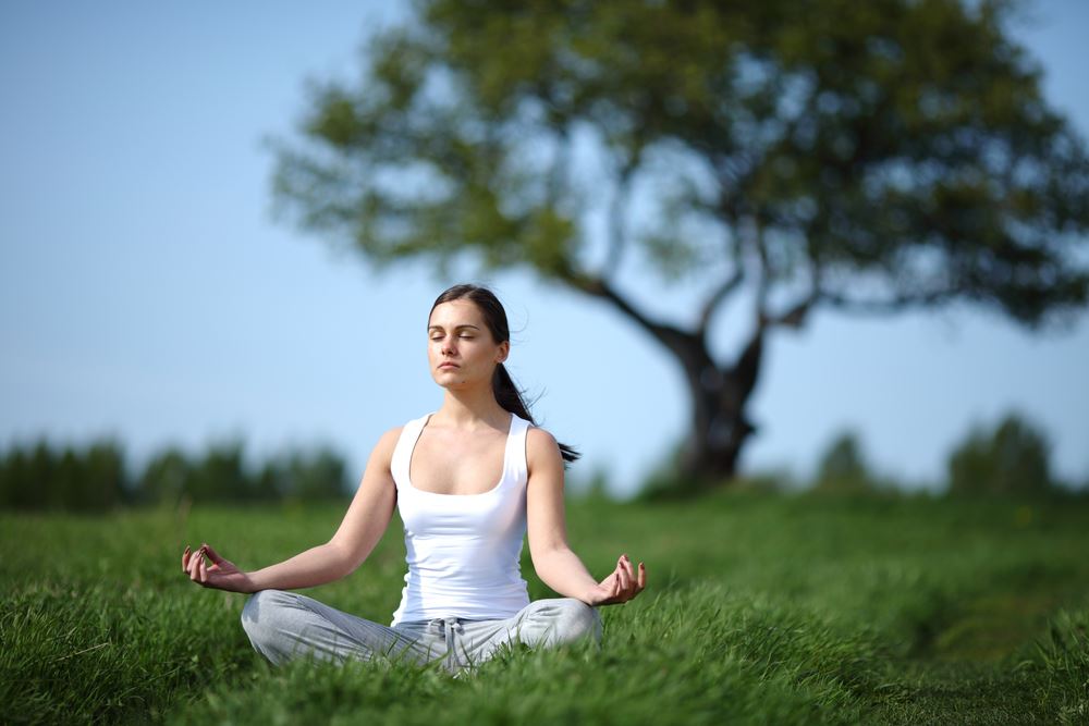 young girl training yoga on sunny meadow